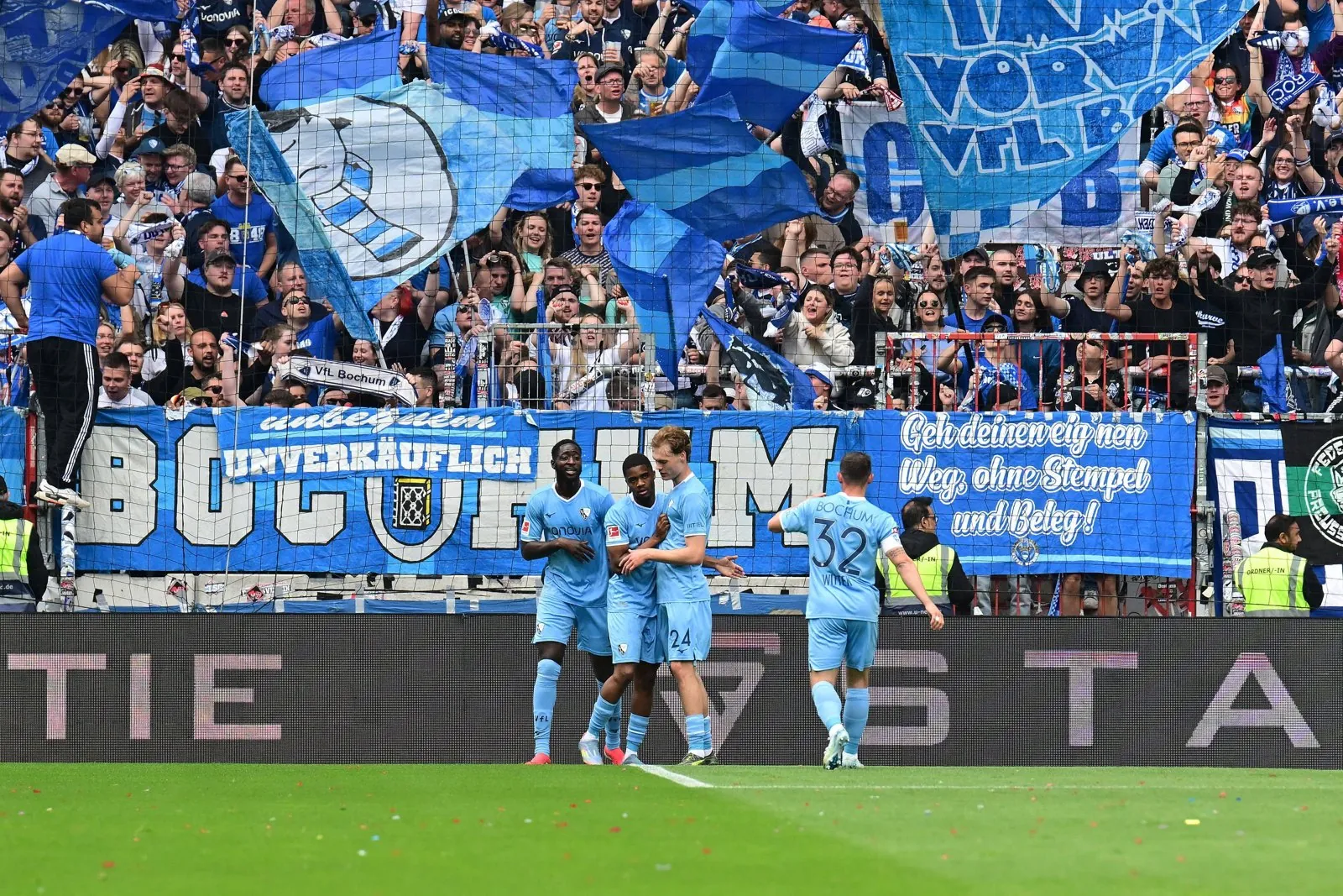 VfL Bochum players celebrating in front of the blue-and-white fan stand